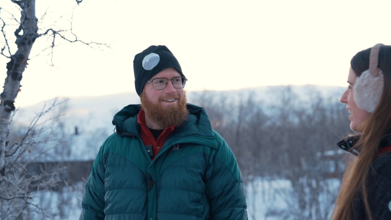 Aril Petersson speaks to Rachel Schnalzer with the mountains of Abisko in the background