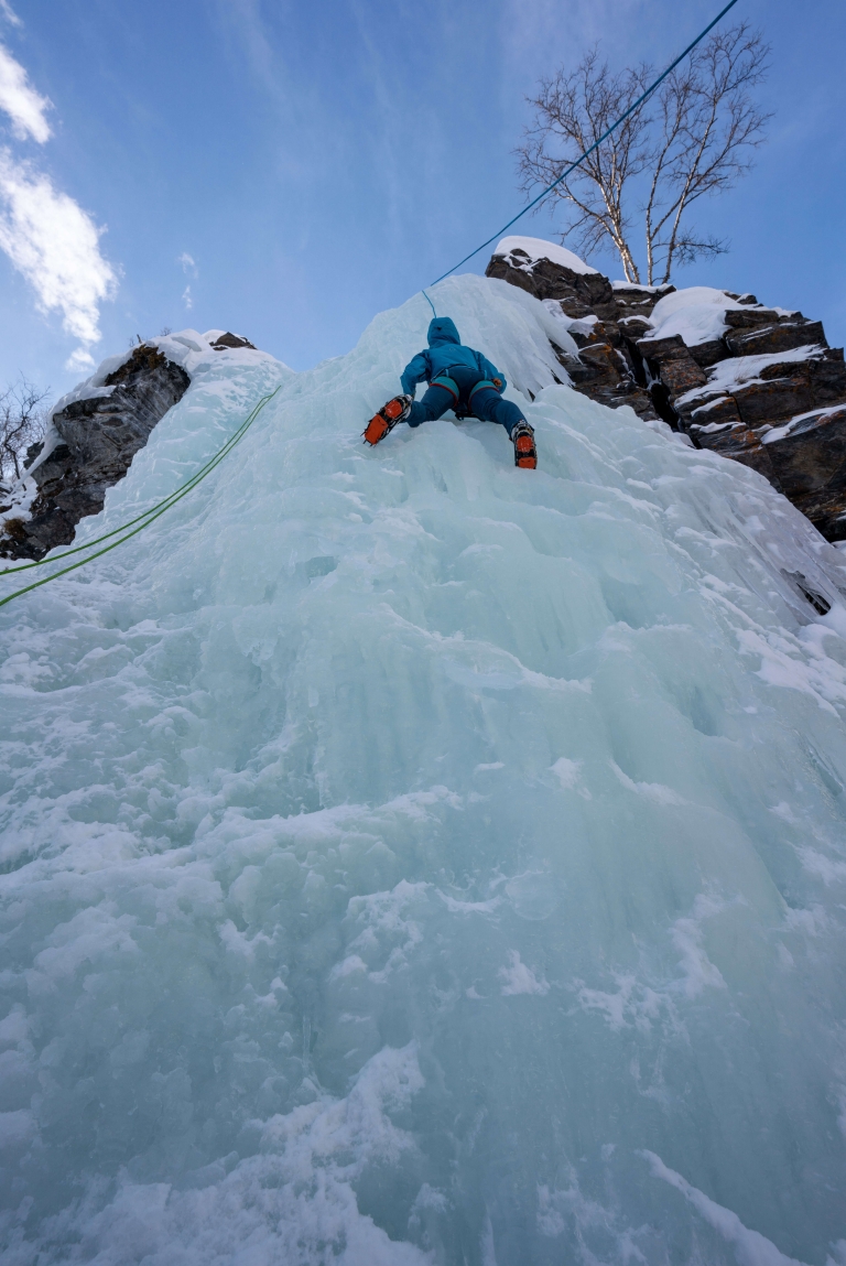 An ice climber climbs a wall of ice in Abisko, Sweden