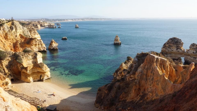 ポルトガル、ラゴスの太陽が降り注ぐ崖、砂浜、水域
