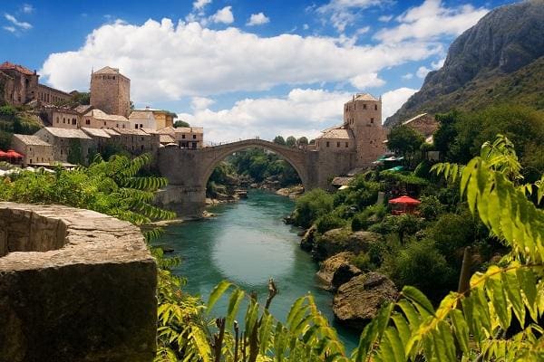 Puente viejo en Mostar, rodeado de exuberantes laderas